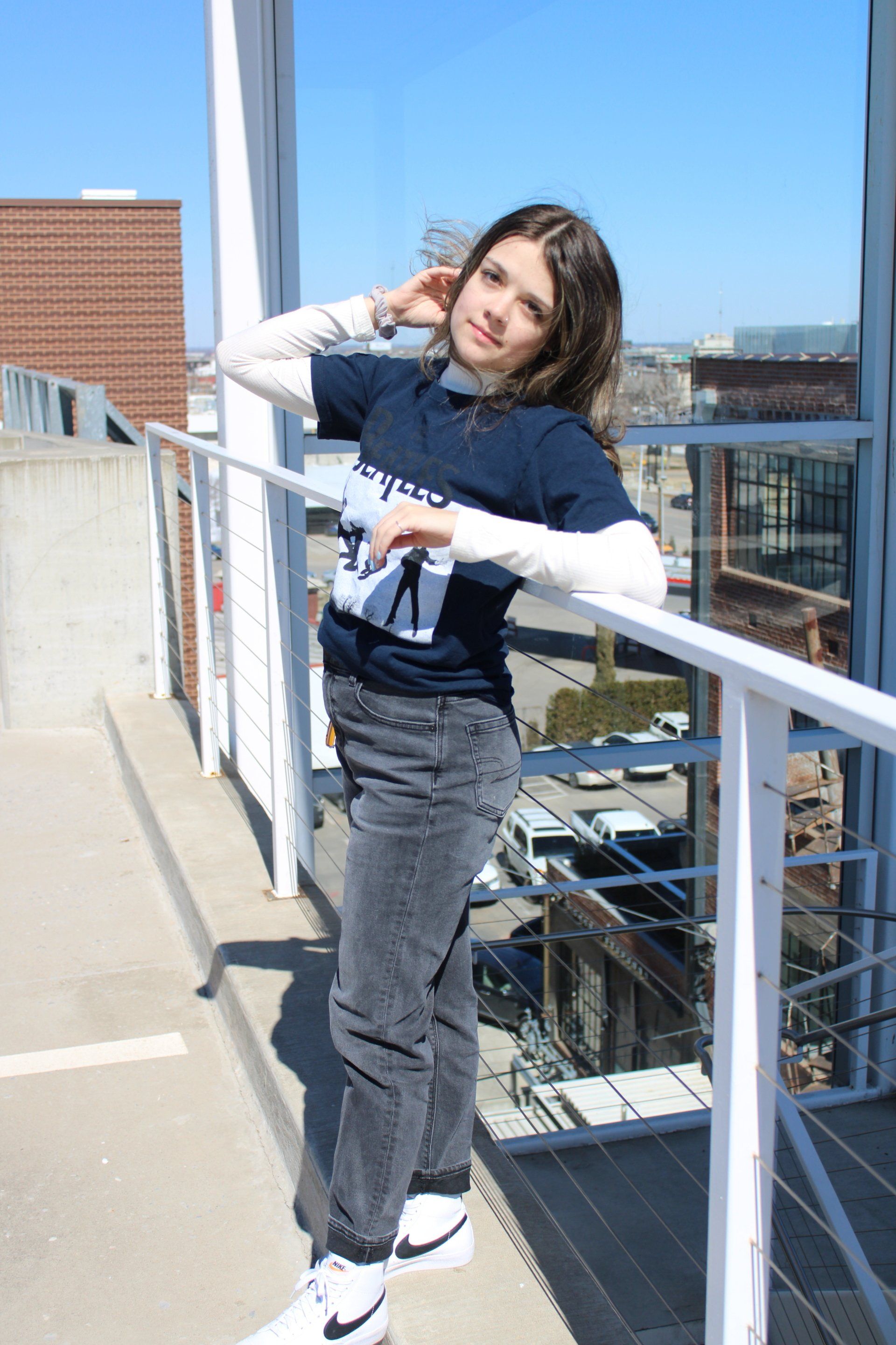 A woman is standing on a balcony leaning on a railing.