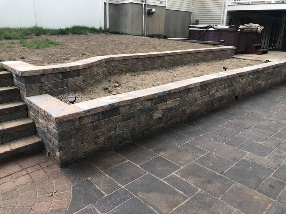 Backyard with raised brick retaining walls and steps around a paved patio area