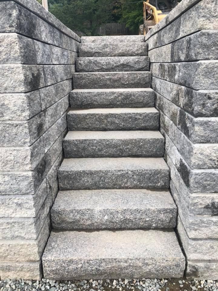 Stone steps between gray retaining walls leading upward outdoors