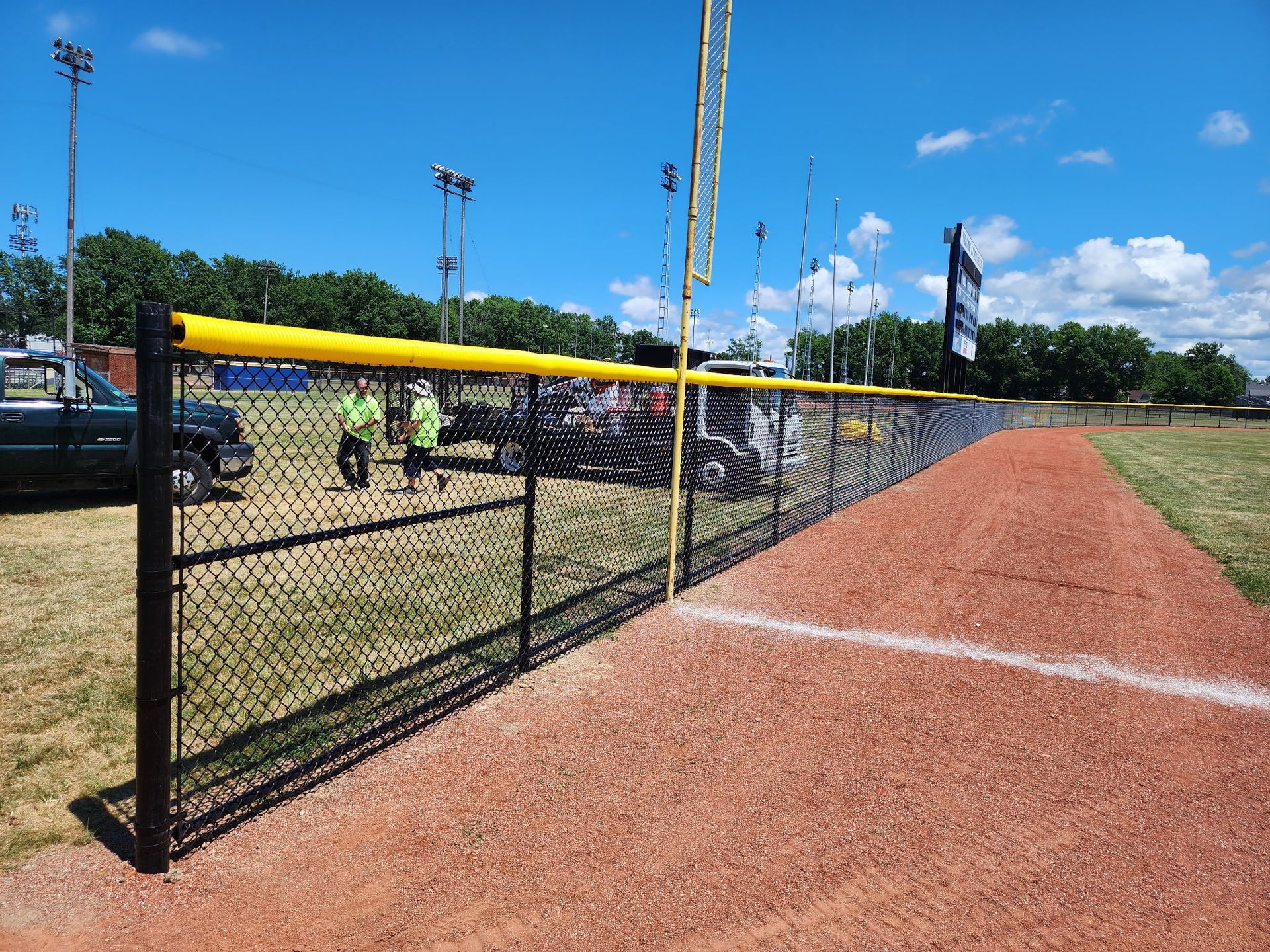 A chain link fence surrounds a baseball field on a sunny day.