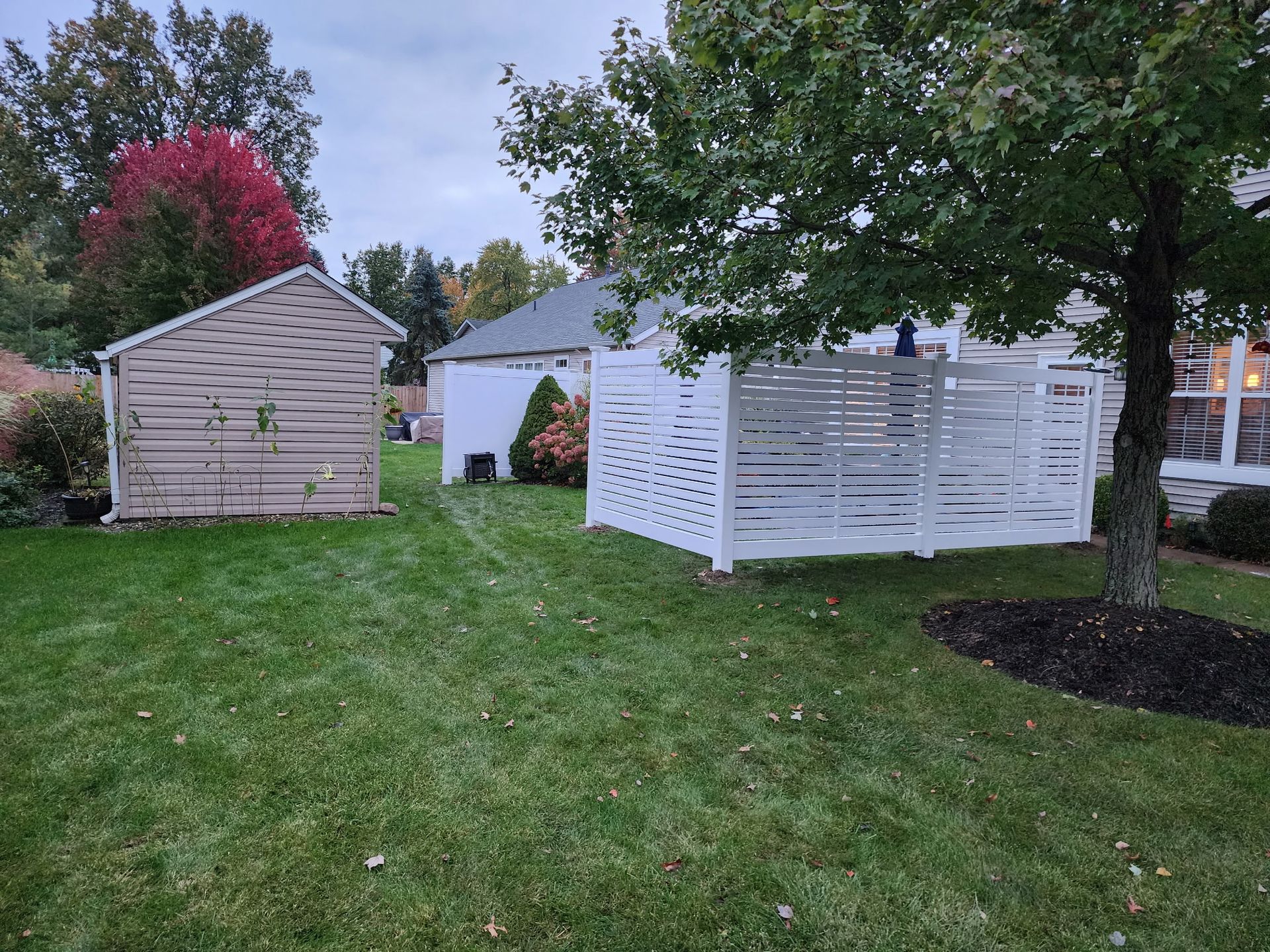 There is a white fence in the backyard of a house.