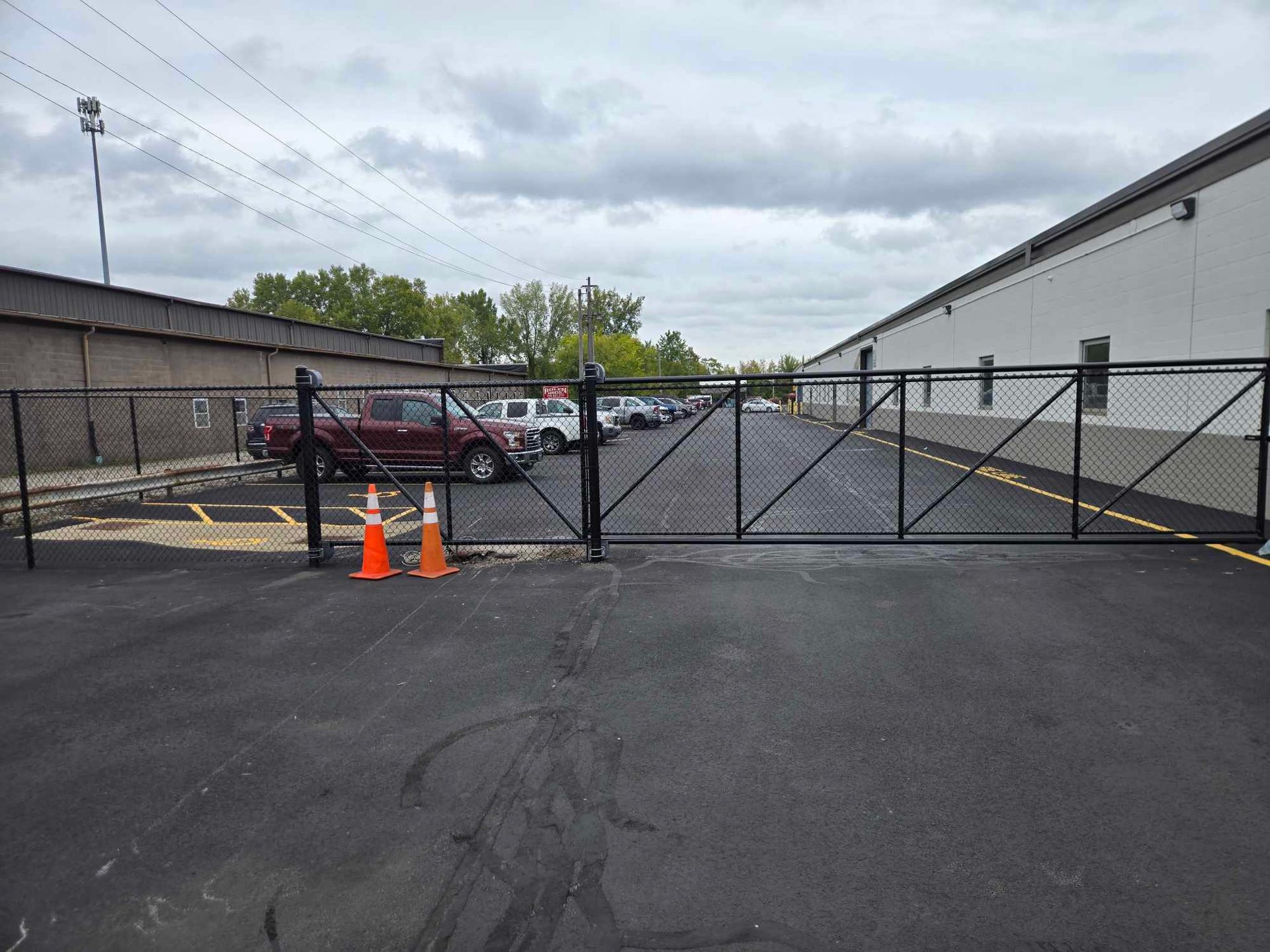 A parking lot with a fence and cones in front of it.