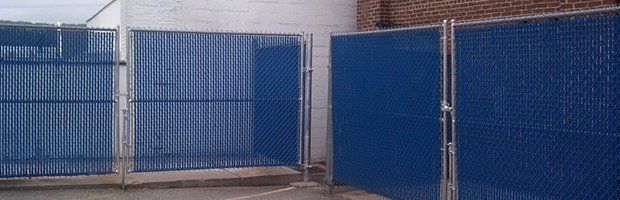 A blue chain link fence is surrounding a building.