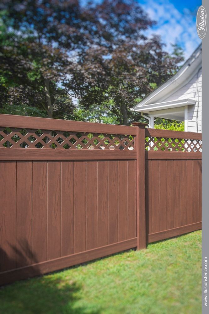 A brown wooden fence is sitting on top of a lush green lawn in front of a house.