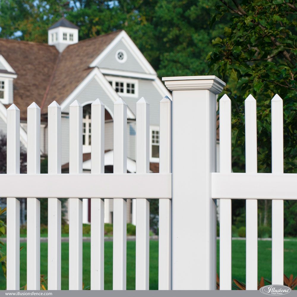 A white picket fence with a house in the background