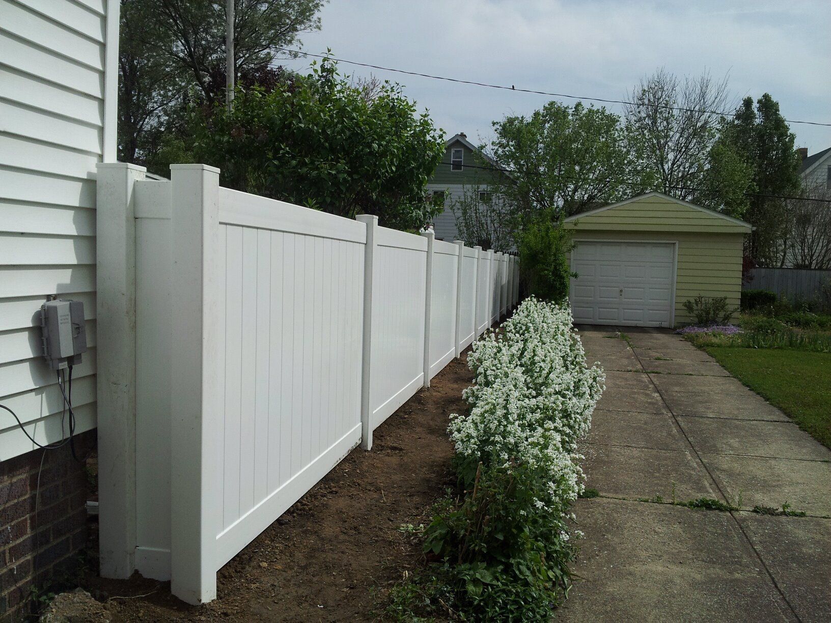A white fence along the side of a house