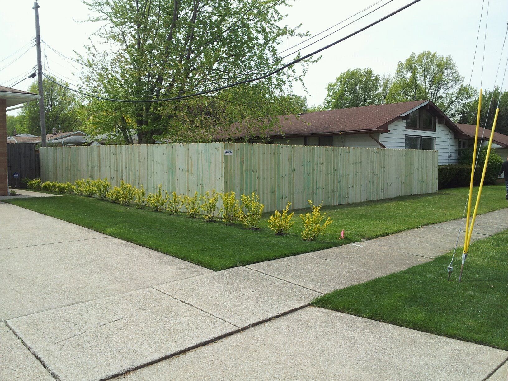 A wooden fence surrounds a lush green yard in front of a house