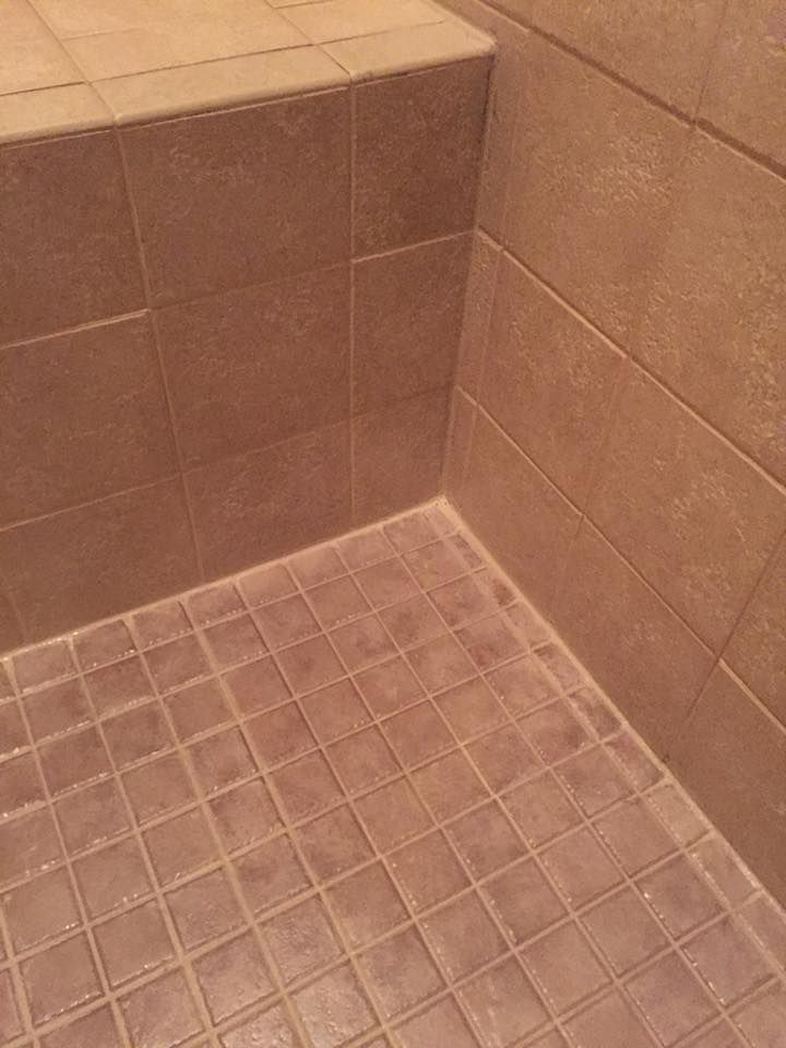 Brown tiled shower with a step and corner.