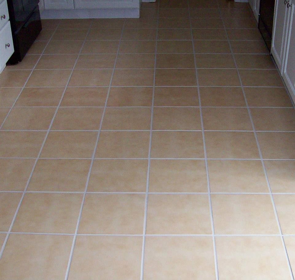 Tan square tile floor in a kitchen setting with white grout.