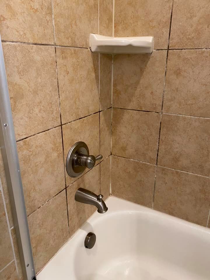 Bathtub with tan tile surround, faucet, and soap dish.