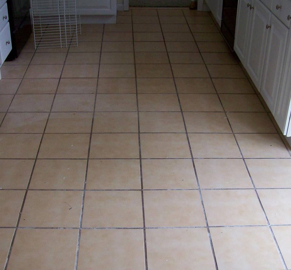 Tan tile floor in a kitchen with white cabinets visible.