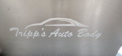 Logo for Tripp's Auto Body, white text and car outline on a grey surface.