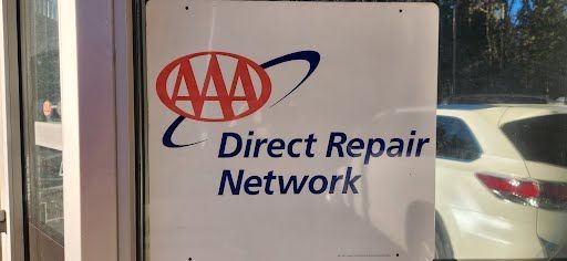 Sign for AAA Direct Repair Network on a door, with a white vehicle visible through the window.