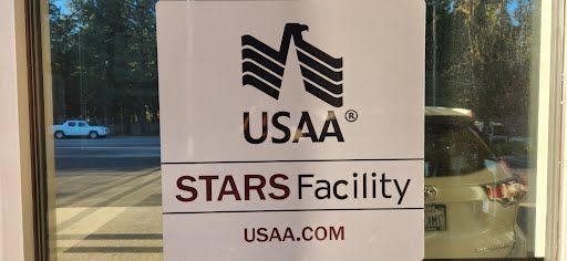 Sign on a glass door for USAA's STARS Facility, USAA.com. A white car and trees are visible through the glass.