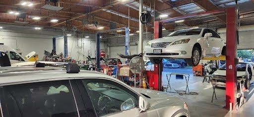 A car repair shop with a car on a lift. Tools and equipment are scattered around the shop.