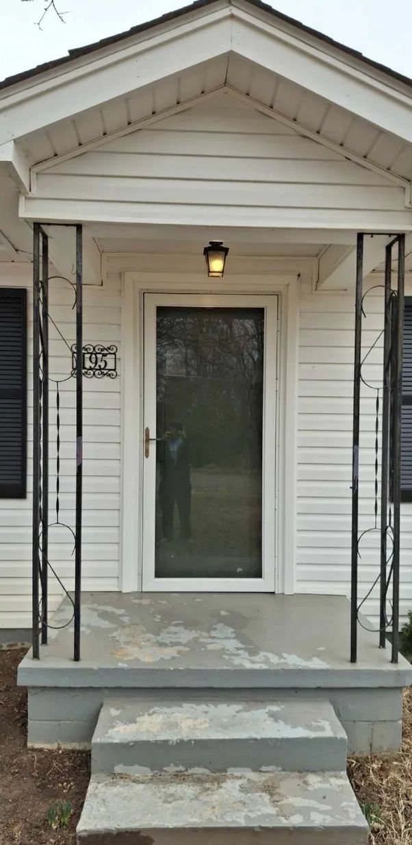 White house entrance with steps and ornate black iron supports.