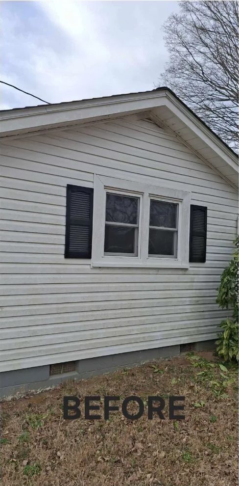 Side view of a white house with black shutters on the windows. 