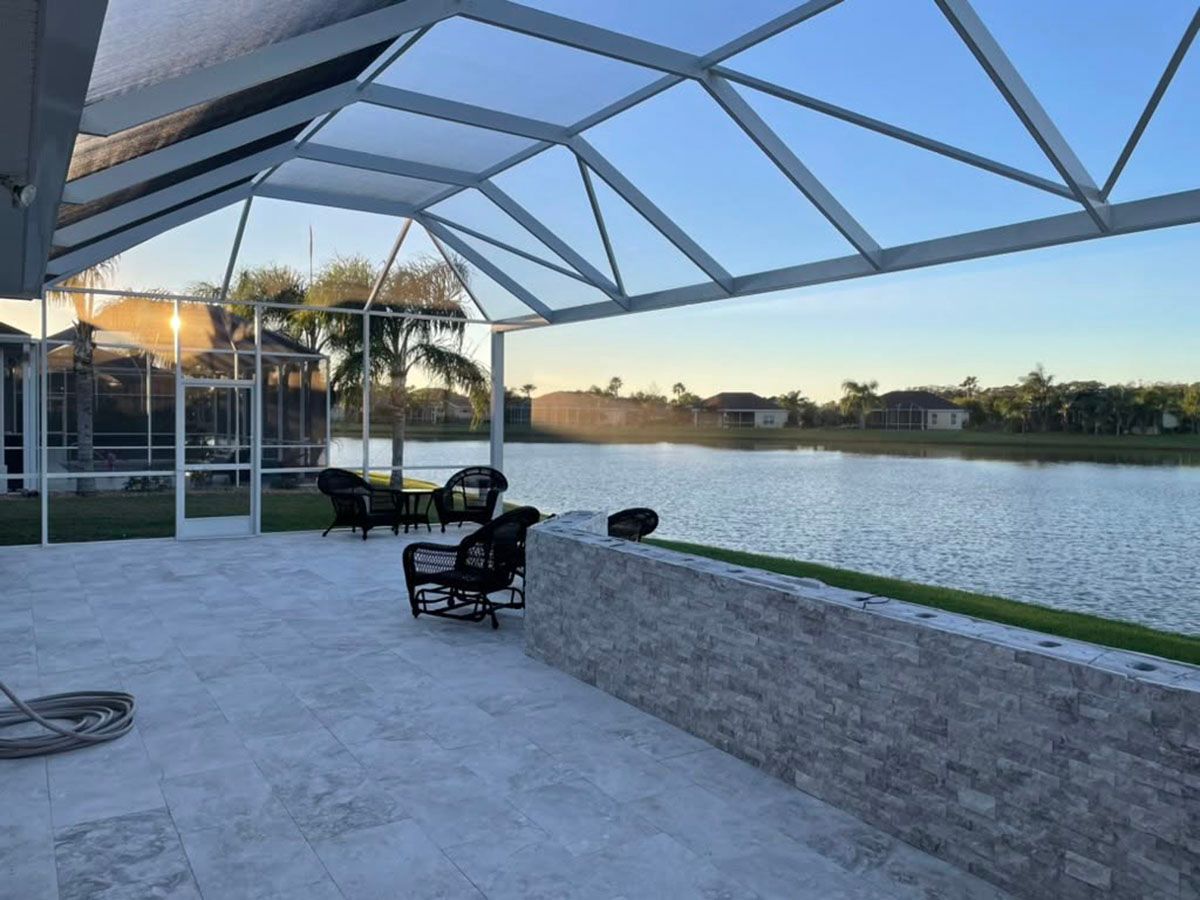 Covered patio with chairs overlooking a calm lake at sunset