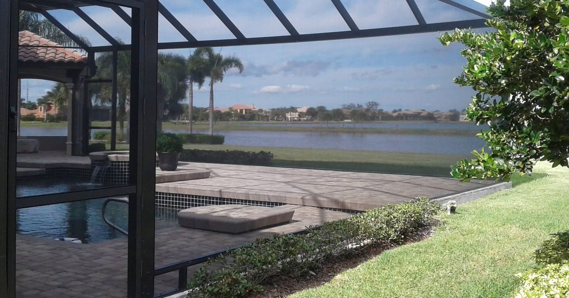 Poolside patio with pergola, lounge chairs, and waterfront view across calm blue water