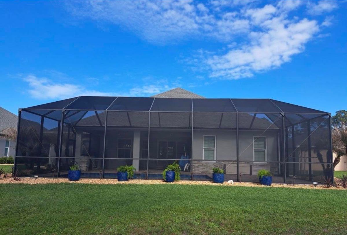 Screened-in patio enclosure with blue flower pots under a bright blue sky