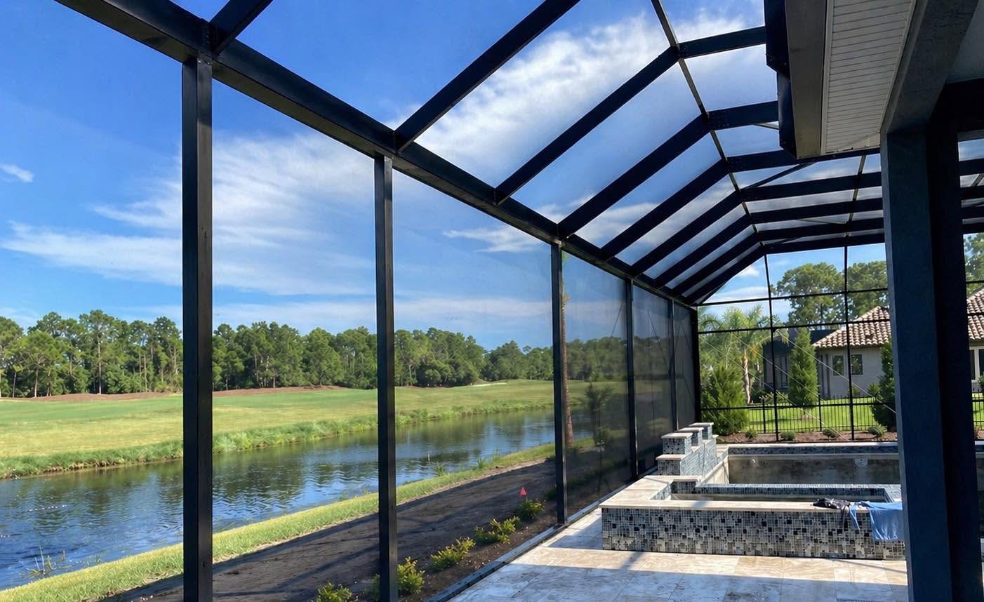 Screened patio overlooking a pond and grassy field under a blue sky