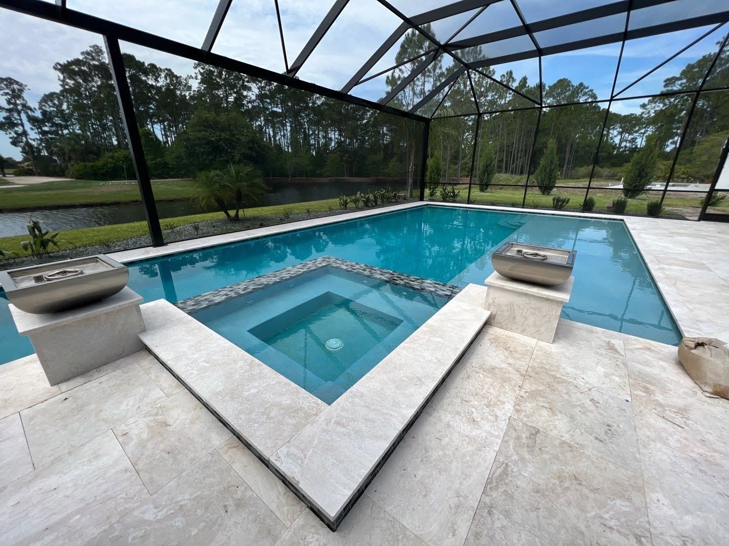 Screened backyard pool with a central spa and stone deck