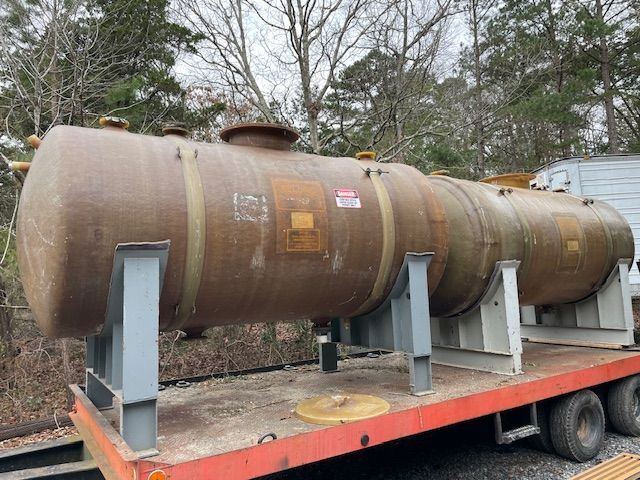 Large cylindrical industrial tank on a flatbed trailer, brown with metal supports, outdoors.