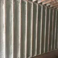 Vertical corrugated metal wall, weathered with light and shadow.