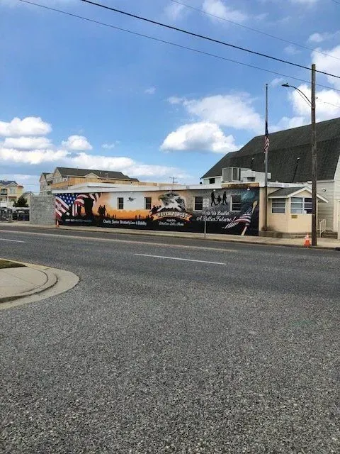 A building with a large mural of military imagery; a street in front, overcast sky.