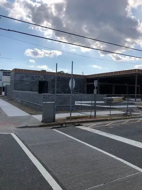 Building under construction, grey block walls, exposed wood framing, crosswalk, utility poles.