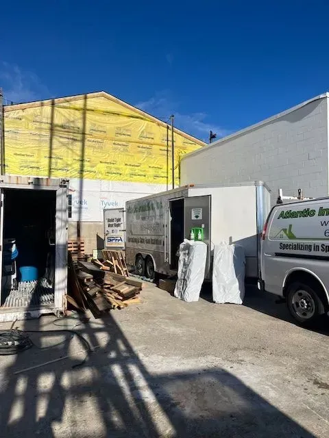 Construction site with a trailer, white truck, and a building under renovation.