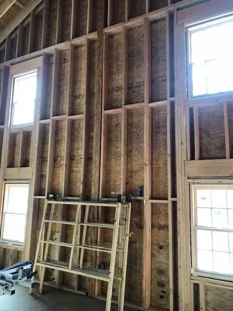 Interior of a building under construction, wooden frame with windows and unfinished walls.