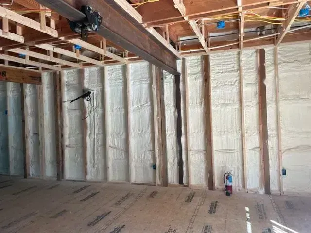 Interior of a building with wooden studs and spray foam insulation on the walls.