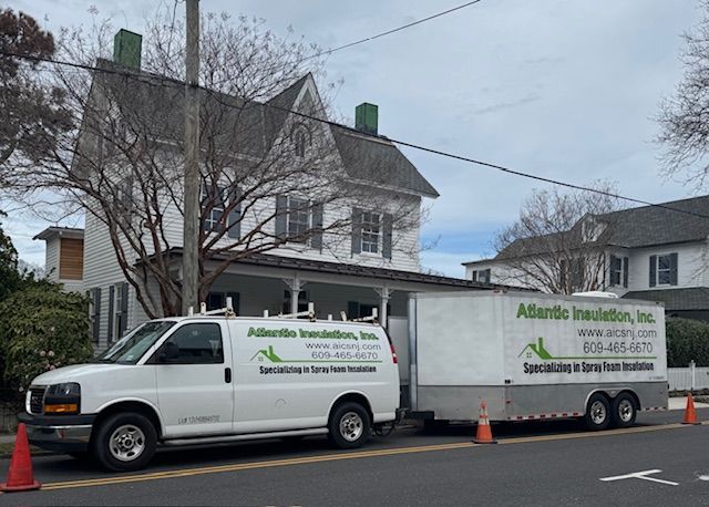 White van and trailer for Atlantic Insulation, Inc. parked in front of a white house.