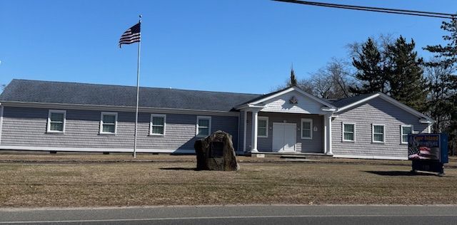 A gray building with an American flag flying on a pole on a sunny day.