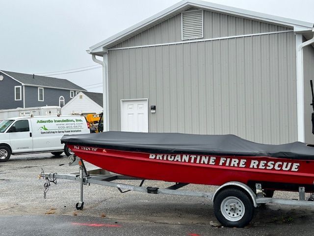 Red Brigantine Fire Rescue boat on a trailer in front of a gray building.