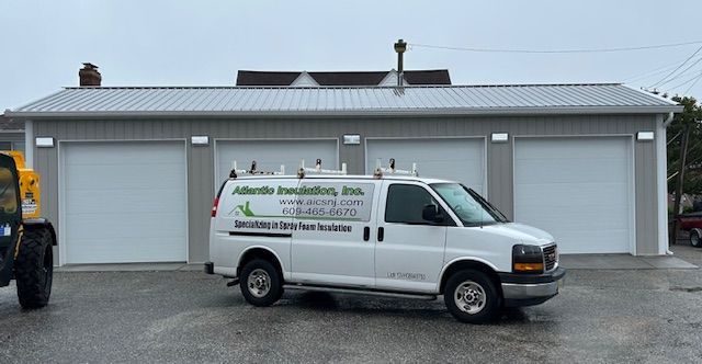 White van with company logo parked in front of three garage bays.