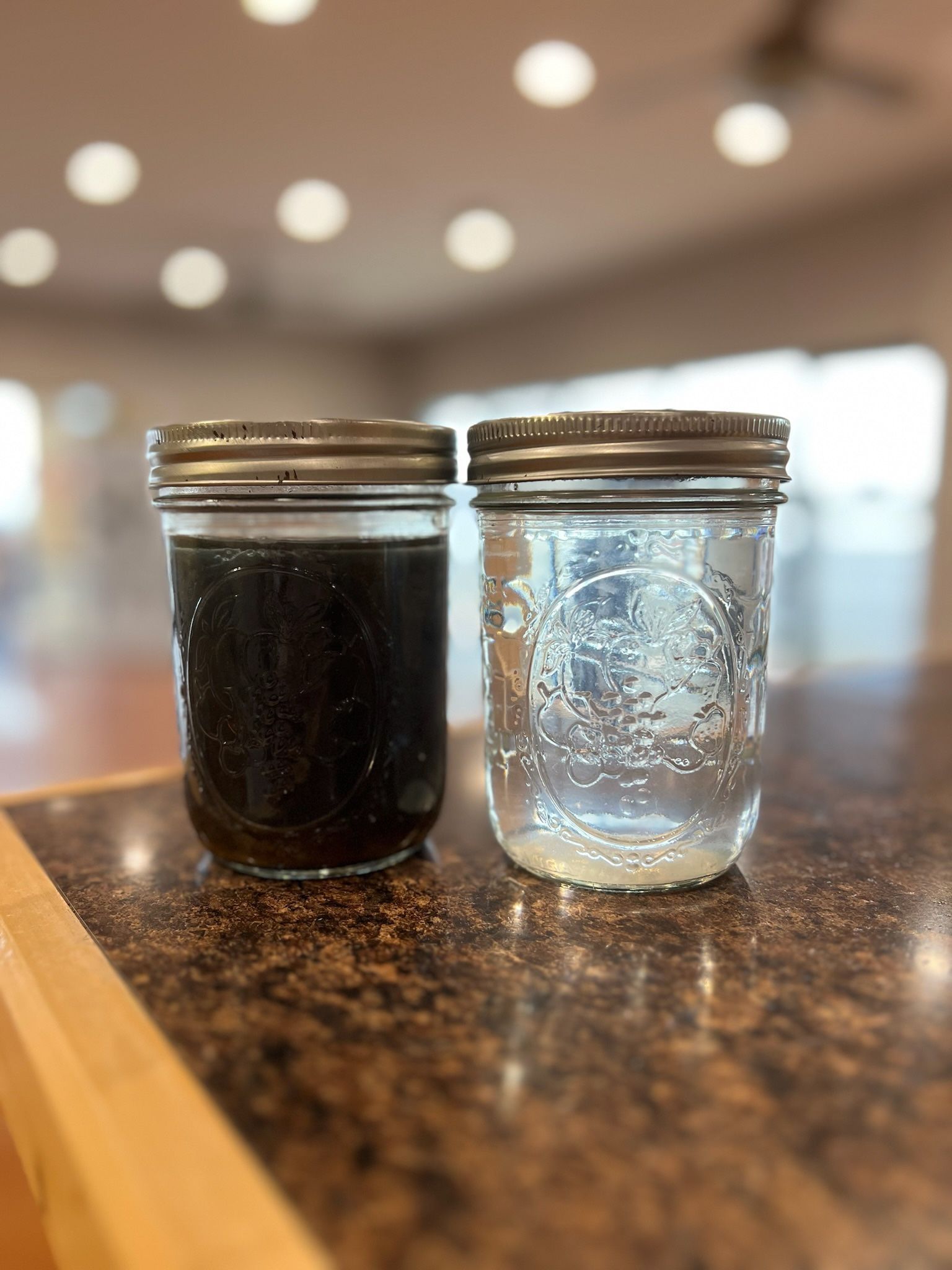 Two jars of different colored liquids are sitting on a counter.