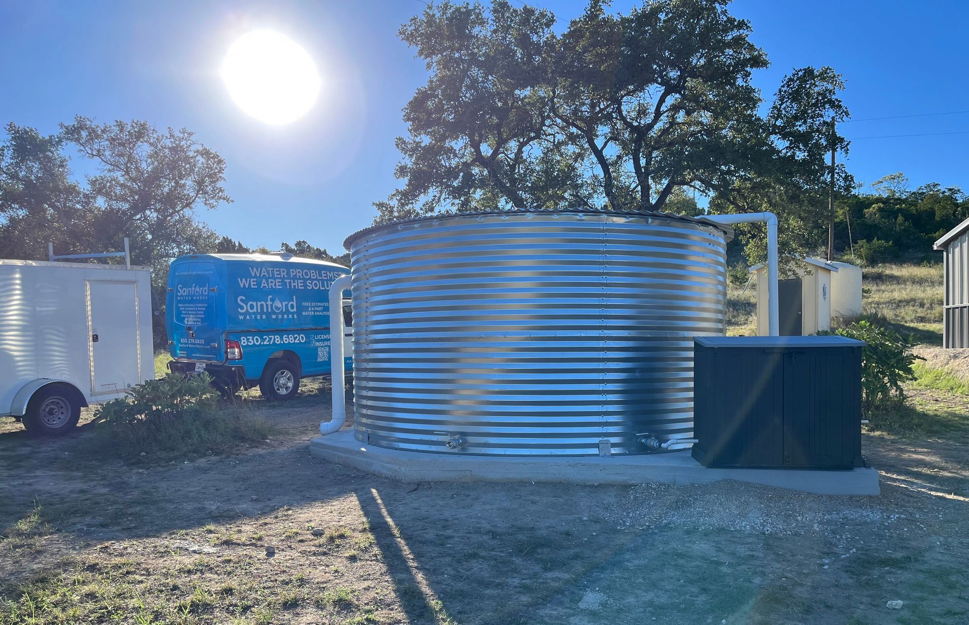 A large metal tank is sitting in a field next to a trailer.