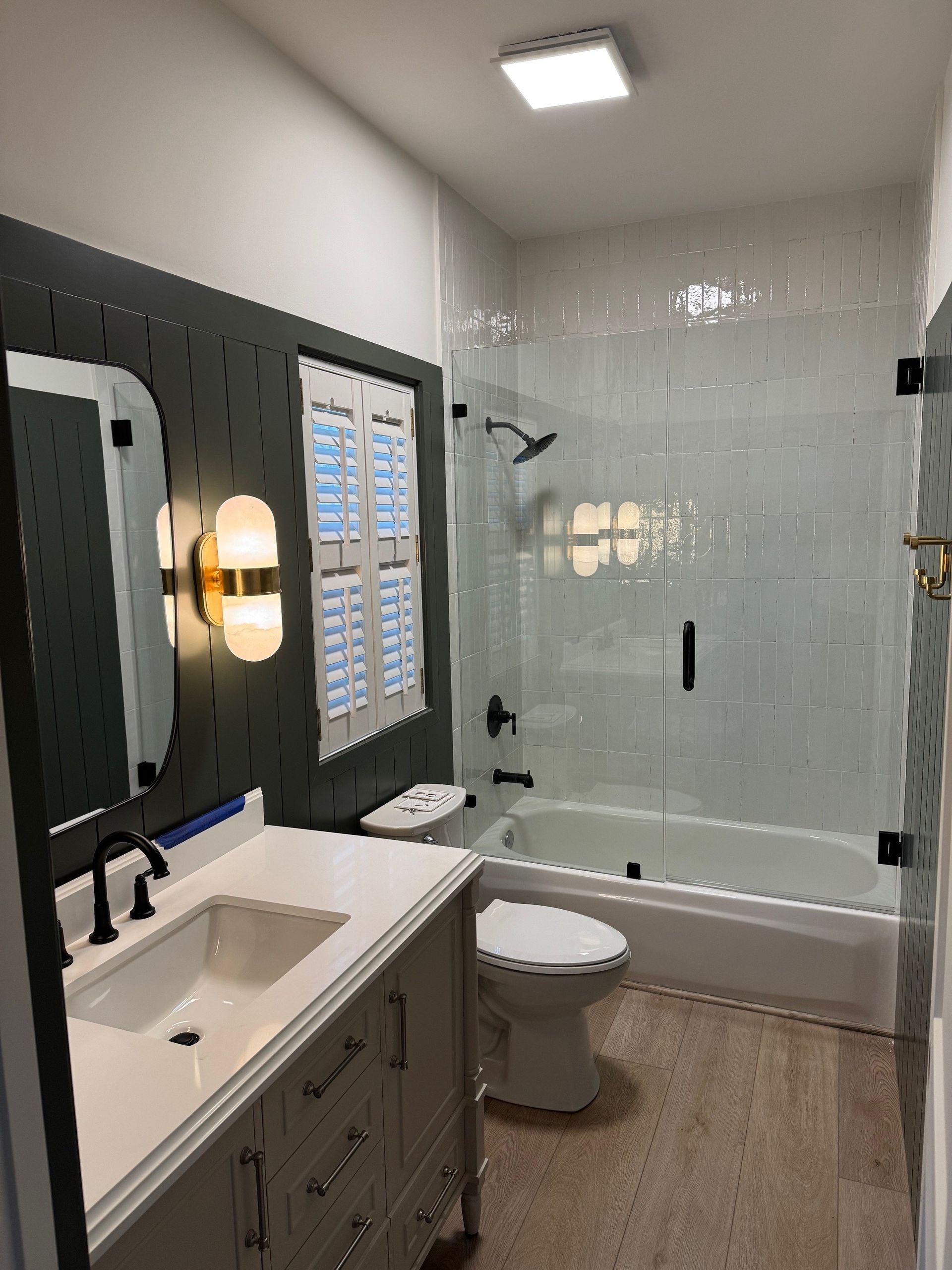 Bathroom with white and black accents: vanity, toilet, tub/shower, decorative wall.