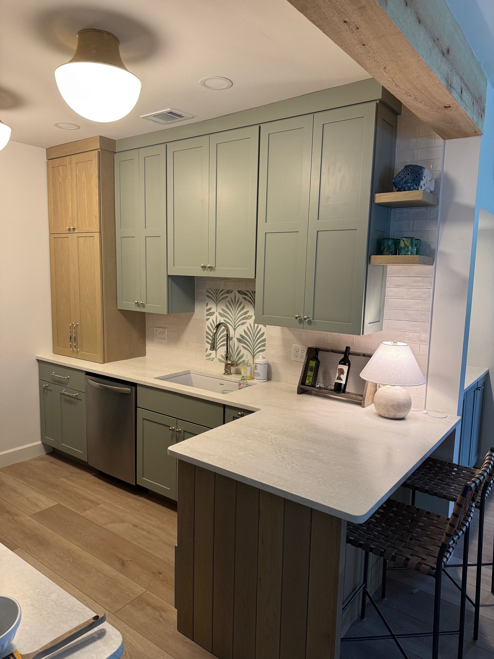 Kitchen with sage green cabinets, light wood accents, and a quartz countertop breakfast bar.