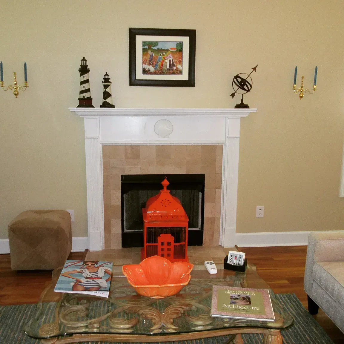 Living room with fireplace, white mantel, orange decorations, and glass coffee table.