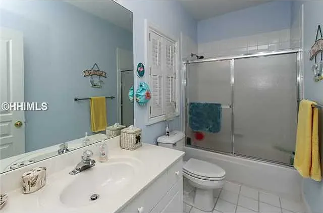 Bathroom with light blue walls, white vanity, toilet, and a shower/tub combo.