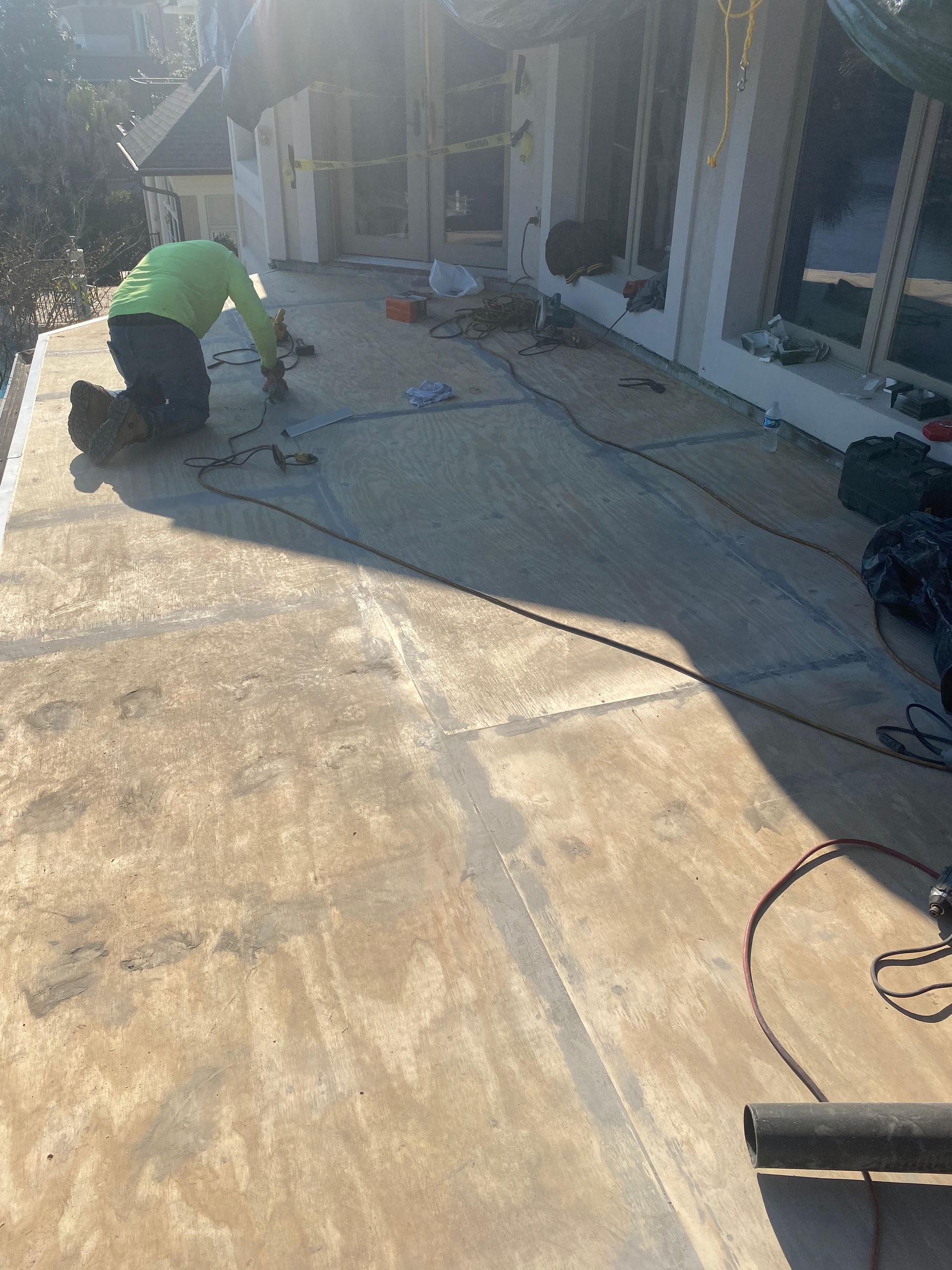 Person in green shirt working on concrete patio. Tools and supplies are scattered around.
