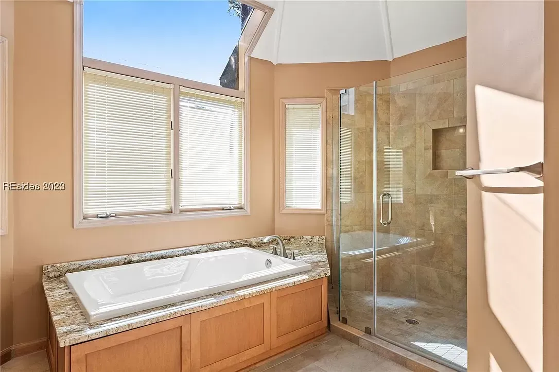 6 Planters - Before: Bathroom with a white bathtub, glass shower, beige walls, and a window with blinds.