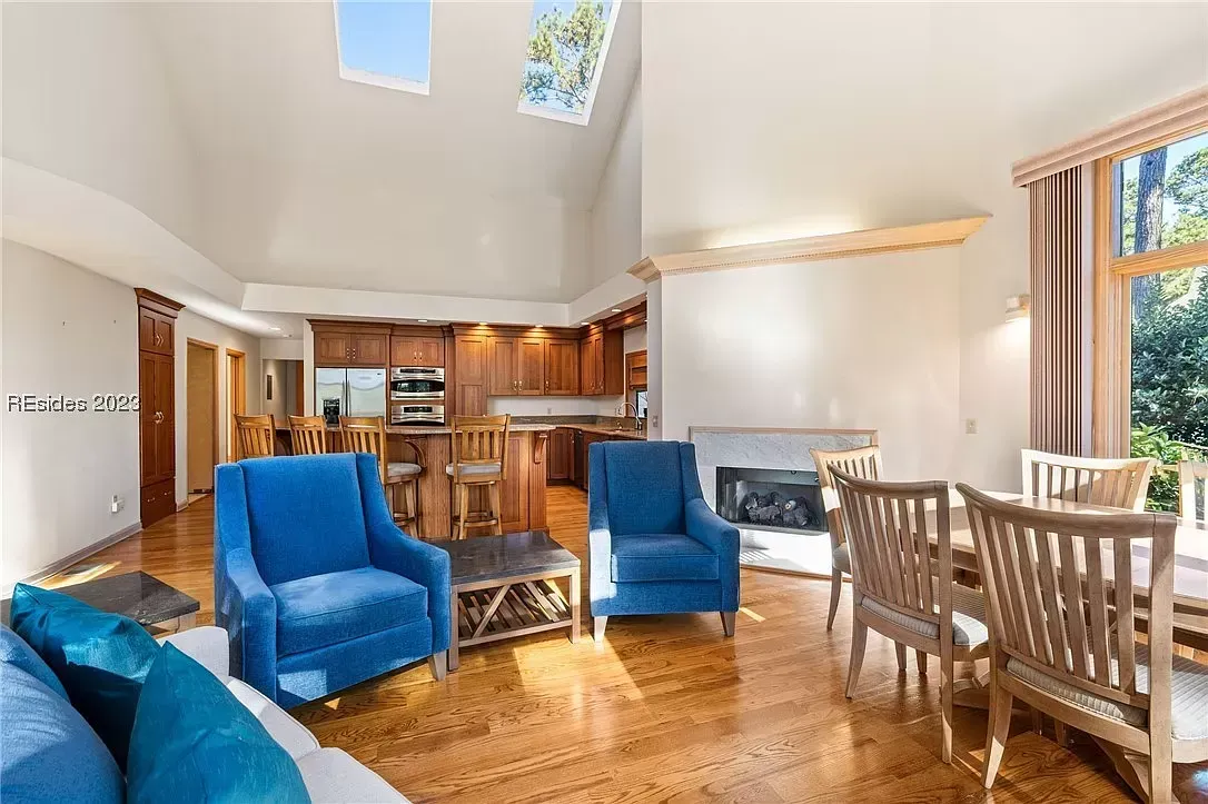 6 Planters - Before: Living room with blue armchairs, dining table, fireplace, and hardwood floors.