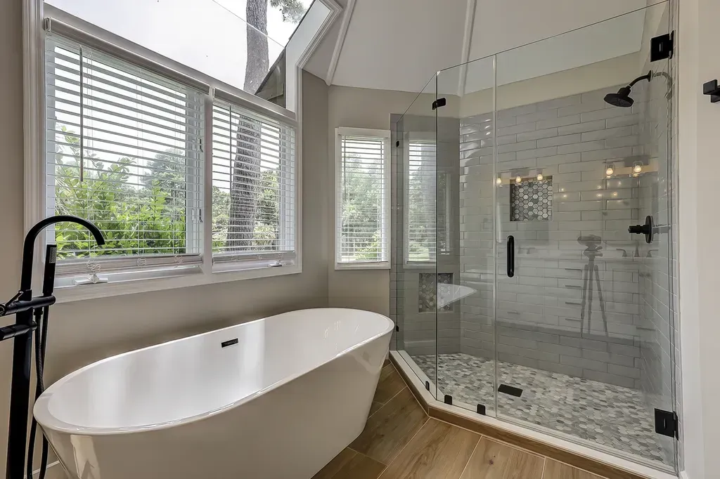 6 Planters - After: Bathroom with white tub, glass shower, and wooden floor. Large windows with blinds.