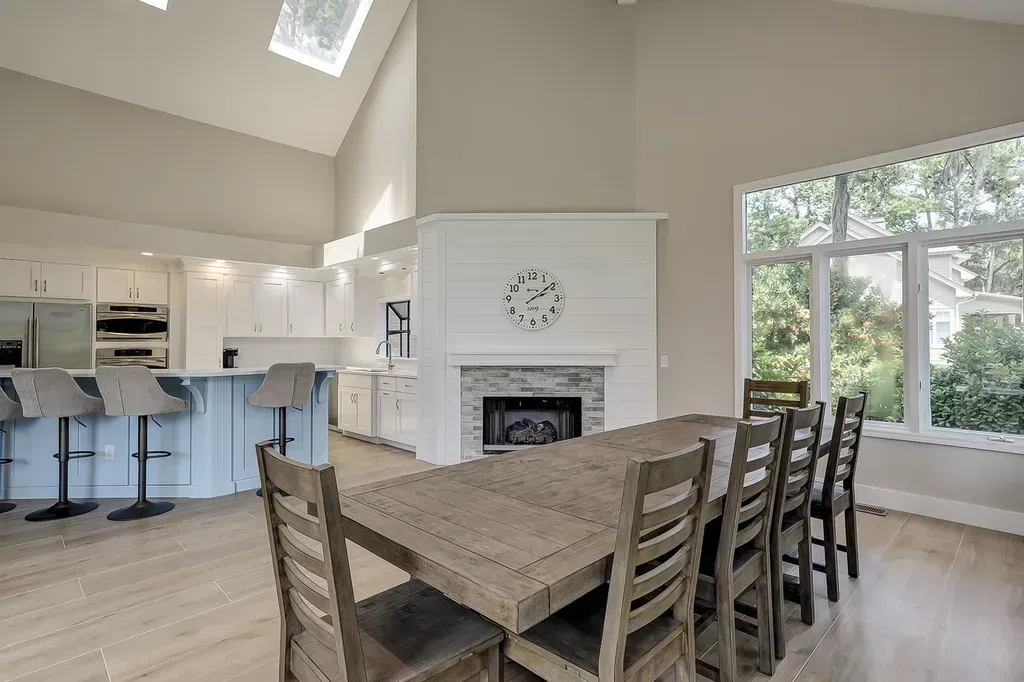 6 Planters - After: Dining room with long wooden table and chairs, kitchen, fireplace, and large window.