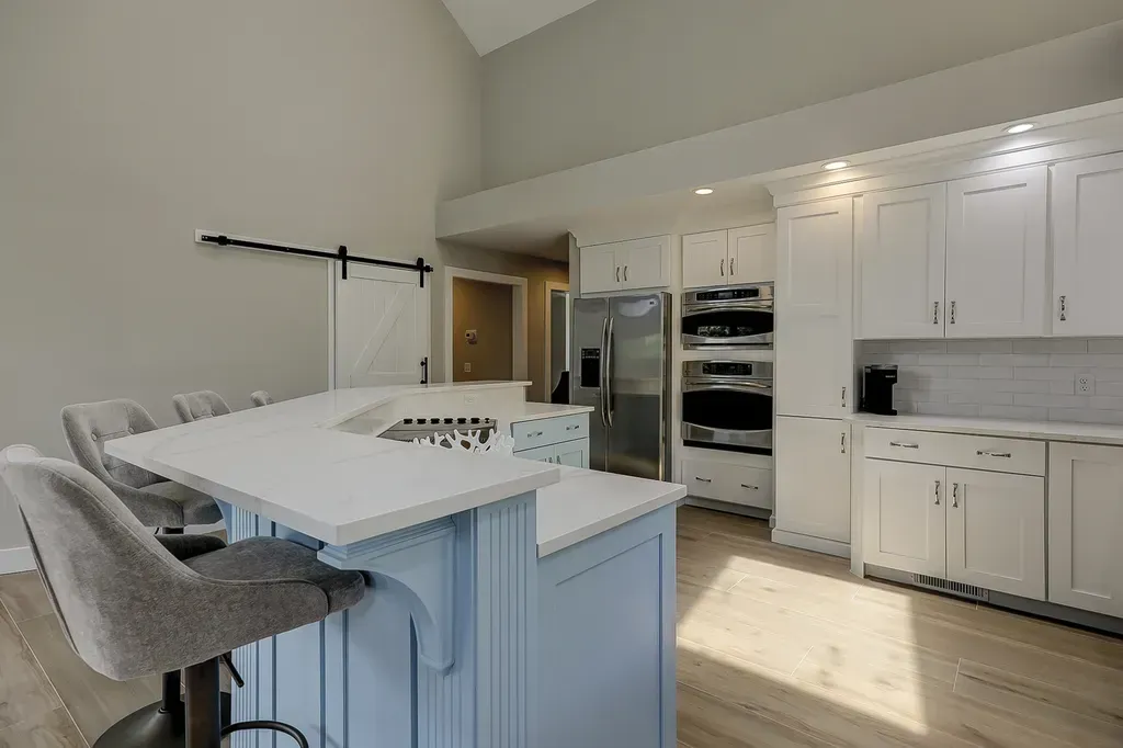 6 Planters - After: Modern kitchen with light blue island, white cabinets, and stainless steel appliances.