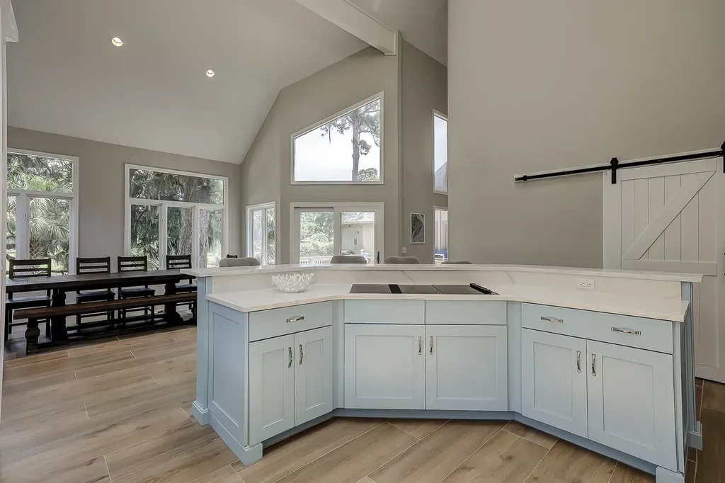 6 Planters - After: Kitchen with light blue cabinets, white countertops, wood floors, dining table, and barn door.